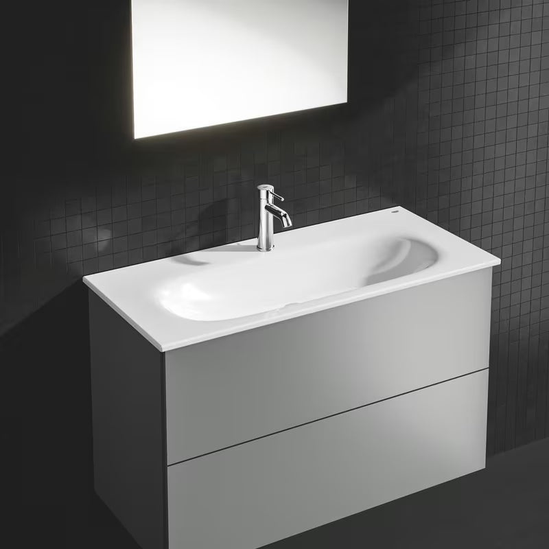 Chromowana jednouchwytowa bateria umywalkowa Grohe Essence New z zestawem odpływowym i zakrzywioną wylewką.