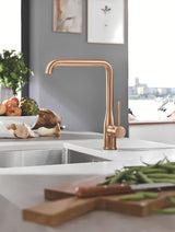 Bateria zlewozmywakowa Grohe Essence New z wysoką obrotową wylewką i wyciąganą wylewką natryskową w wykończeniu brushed warm sunset.