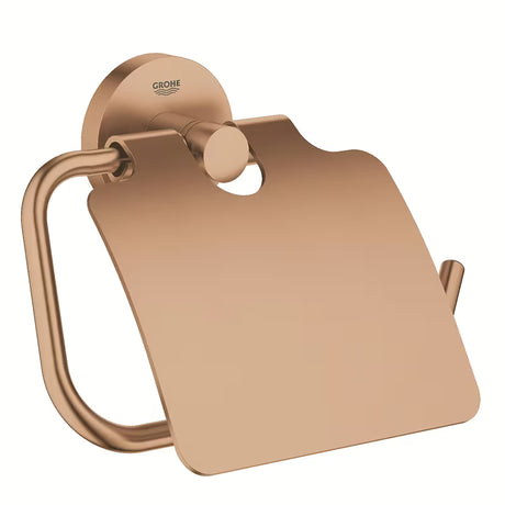 Uchwyt na papier Toaletowy Grohe Essentials z pokrywą w wykończeniu Brushed Warm Sunset z ukrytym mocowaniem.