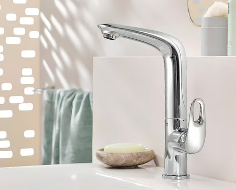 Wysoka jednouchwytowa bateria umywalkowa Grohe Eurostyle New w chromie z obrotową wylewką i zestawem odpływowym.